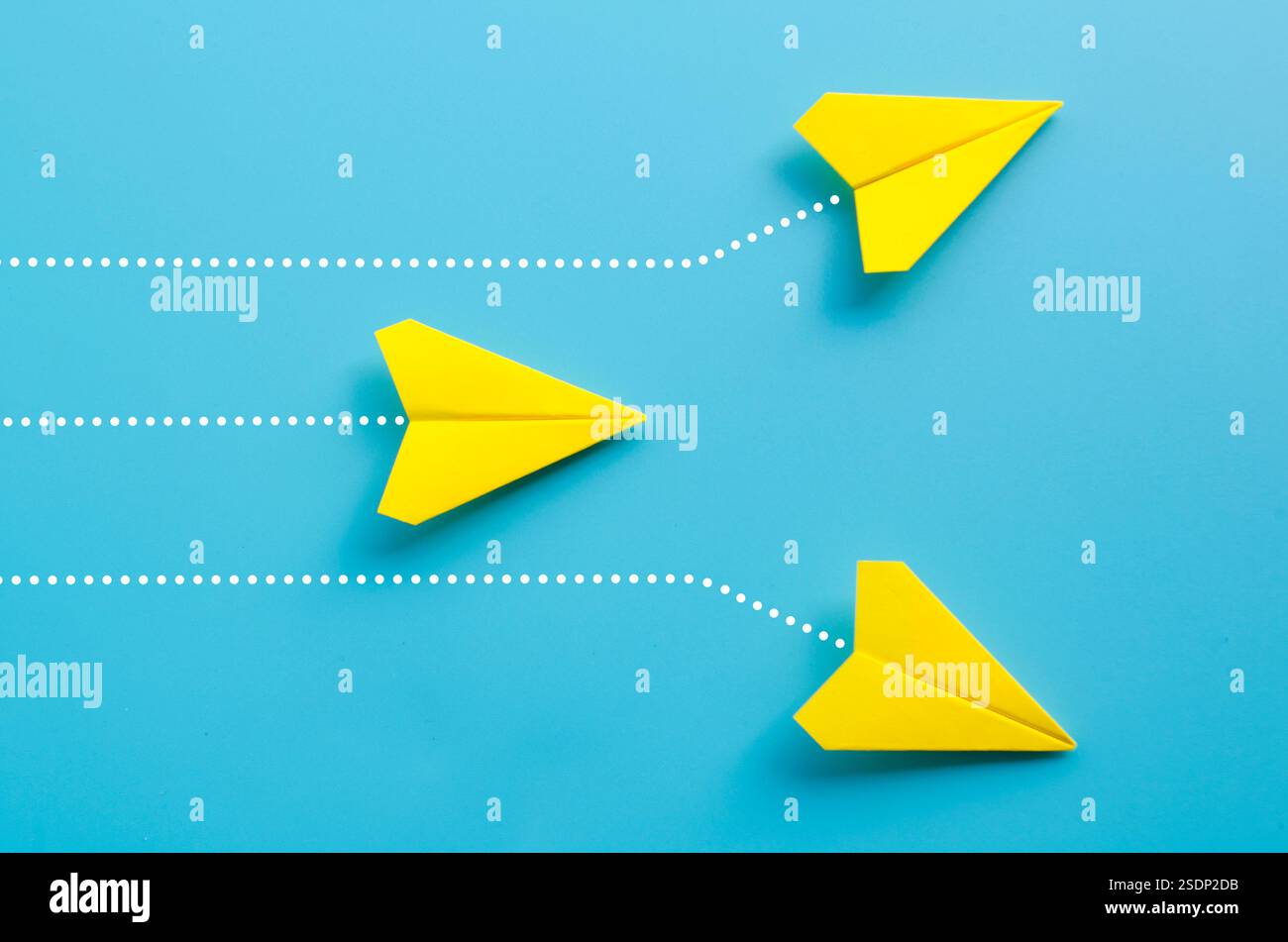 Draufsicht von drei Origami-gelben Papierflugzeugen auf blauem Hintergrund. Stockfoto