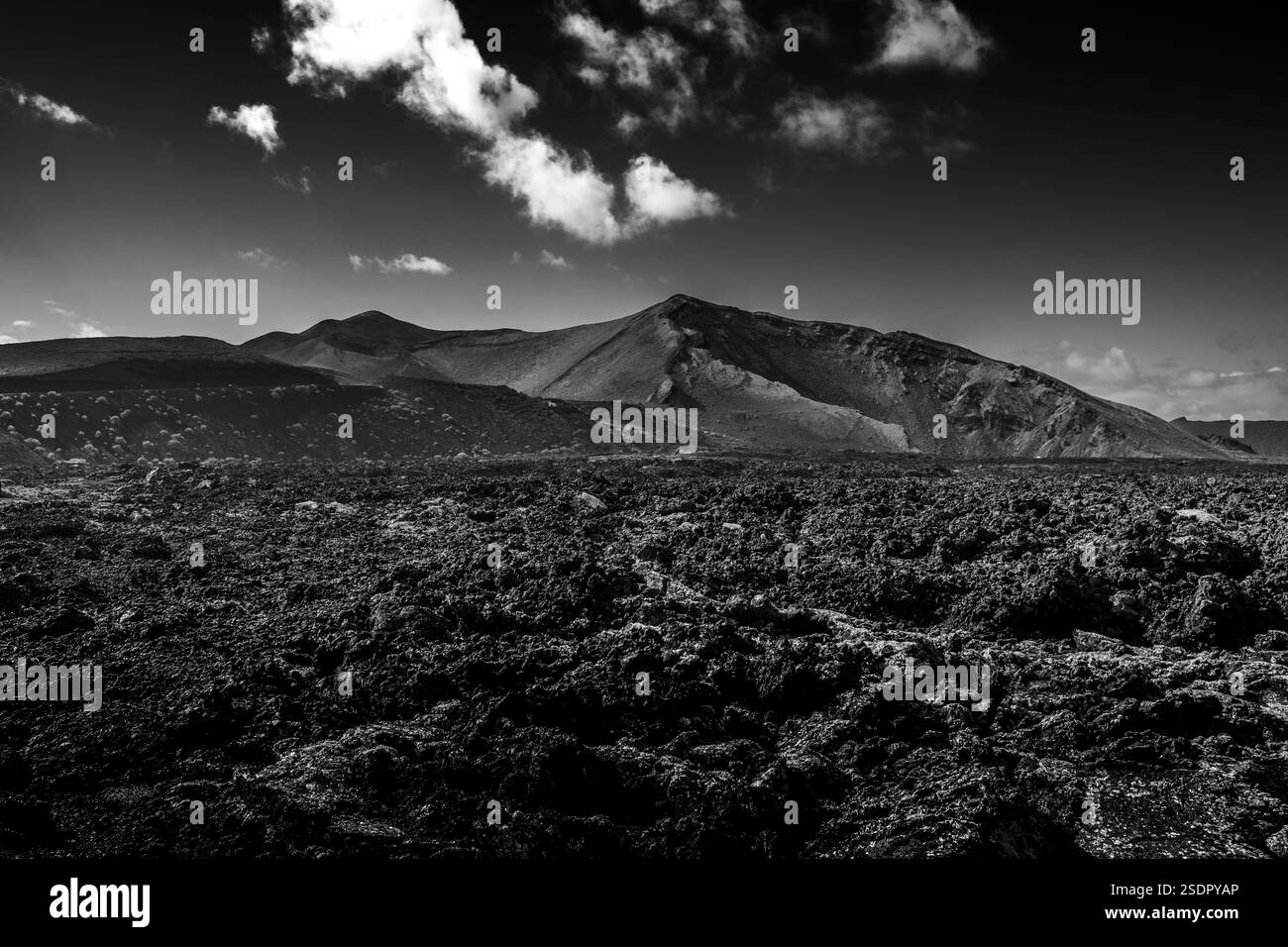 Atemberaubende vulkanische Landschaft mit Ebenholzsand, dramatischen Gipfeln und lebendigem azurblauem Himmel auf Lanzarote. Stockfoto