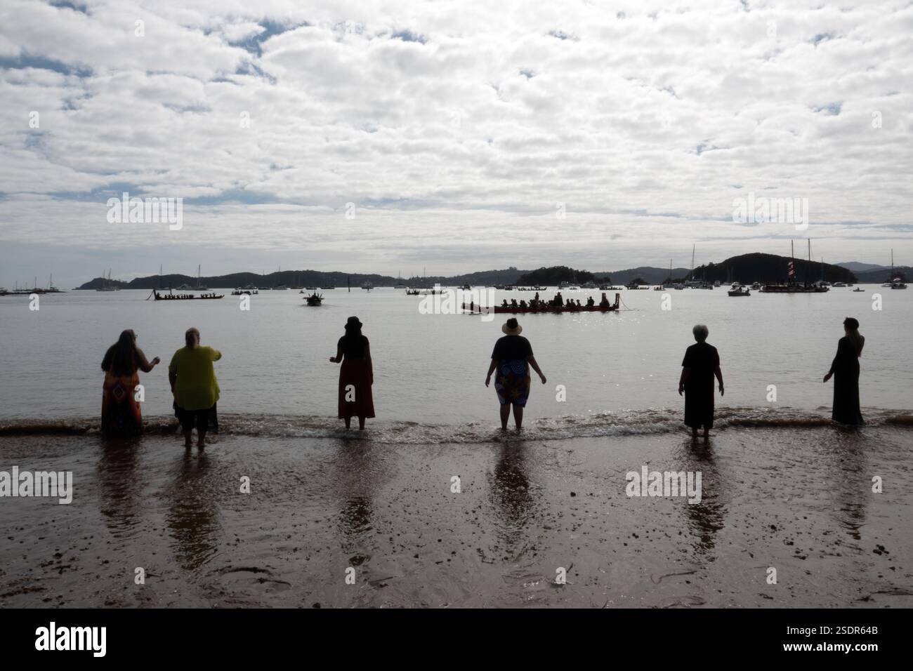 Maori-Frauen singen, während traditionelle Waka am Waitangi Day in der Bay of Islands in Neuseeland vorbeipaddeln Stockfoto
