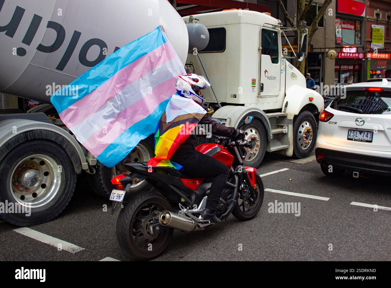 Melbourne, Australien. Februar 2025. Ein Biker kommt an dem Protest vorbei, der mit einer Trans-Flagge und der Progress-Stolz-Flagge fährt. Mitglieder der LGBT-Community in Melbourne und Alliierte marschieren für Trans Rights als Teil des Protect Trans Youth National Day of Action als Reaktion auf die neuen Gesetze der Regierung von Queensland, die Menschen unter 18 Jahren daran hindern, eine geschlechtsbestätigende Betreuung zu beginnen. Quelle: SOPA Images Limited/Alamy Live News Stockfoto