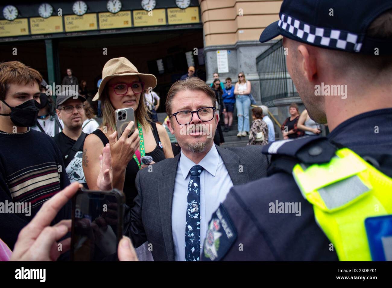 Melbourne, Australien. Februar 2025. Ein Kirchgänger wird von der Polizei von der Kundgebung begleitet, nachdem er die Kundgebung beschuldigt hat, den Gottesdienst in der St. Paul's Cathedral zu stören. Mitglieder der LGBT-Community in Melbourne und Alliierte marschieren für Trans Rights als Teil des Protect Trans Youth National Day of Action als Reaktion auf die neuen Gesetze der Regierung von Queensland, die Menschen unter 18 Jahren daran hindern, eine geschlechtsbestätigende Betreuung zu beginnen. (Foto: Joshua Stanyer/SOPA Images/SIPA USA) Credit: SIPA USA/Alamy Live News Stockfoto