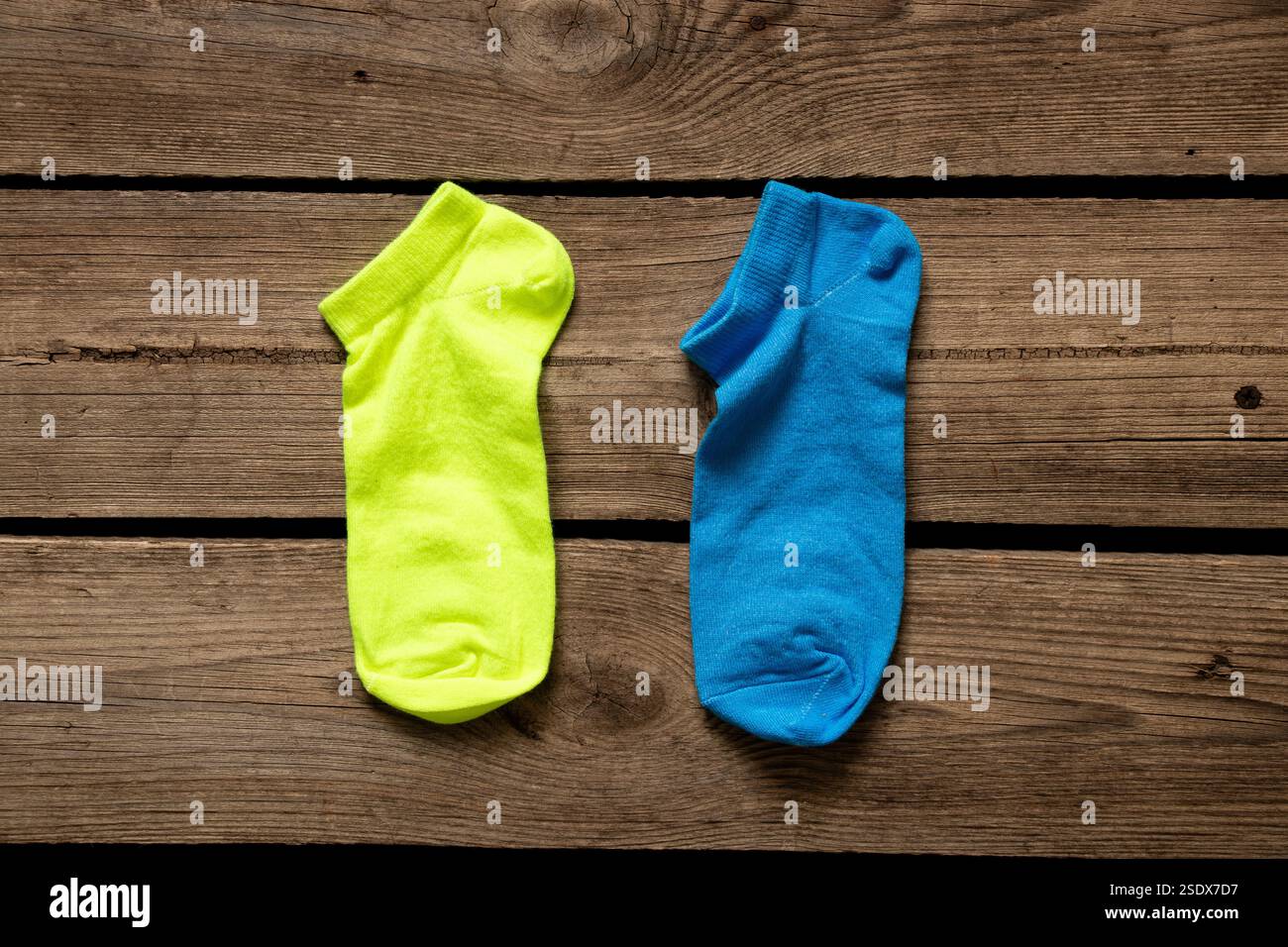 Zwei kurze Damensocken, eine gelbe, eine blaue, liegen zu Hause auf dem Boden, modische Socken Stockfoto