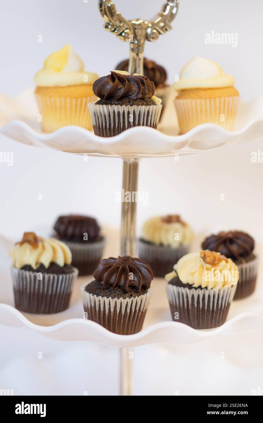 Schokoladen- und Zitronen-Cupcakes auf einem traditionellen Kuchenständer für Oster- und Nachmittagstee; Konzept für Teatime, Geburtstage und Muttertag. Stockfoto