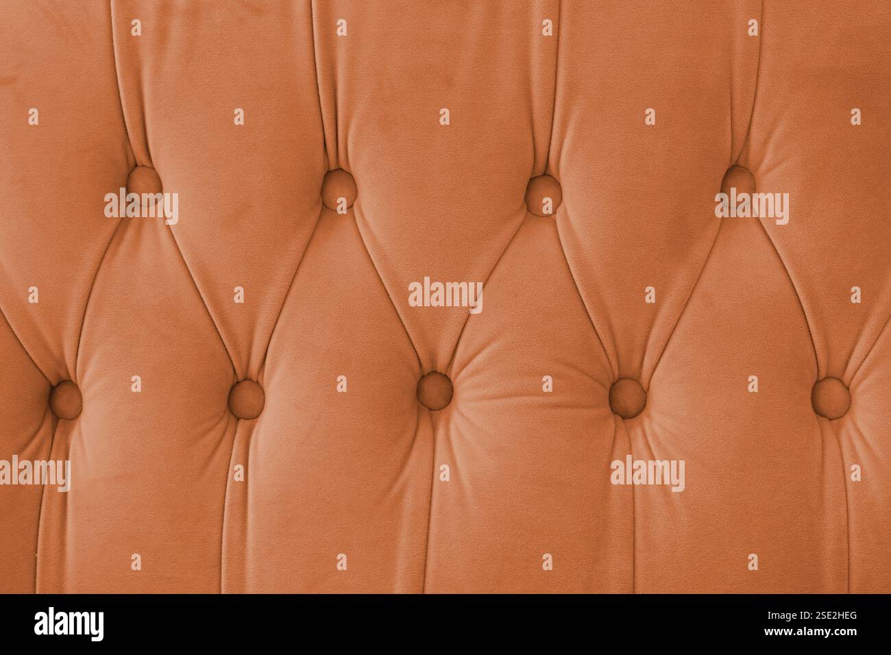 Capitone, rautenkarierter weicher Textilinhalt mit Knöpfen. Klassischer Chesterfield-Retro-Stil, luxuriöser orangefarbener Polsterung Stockfoto