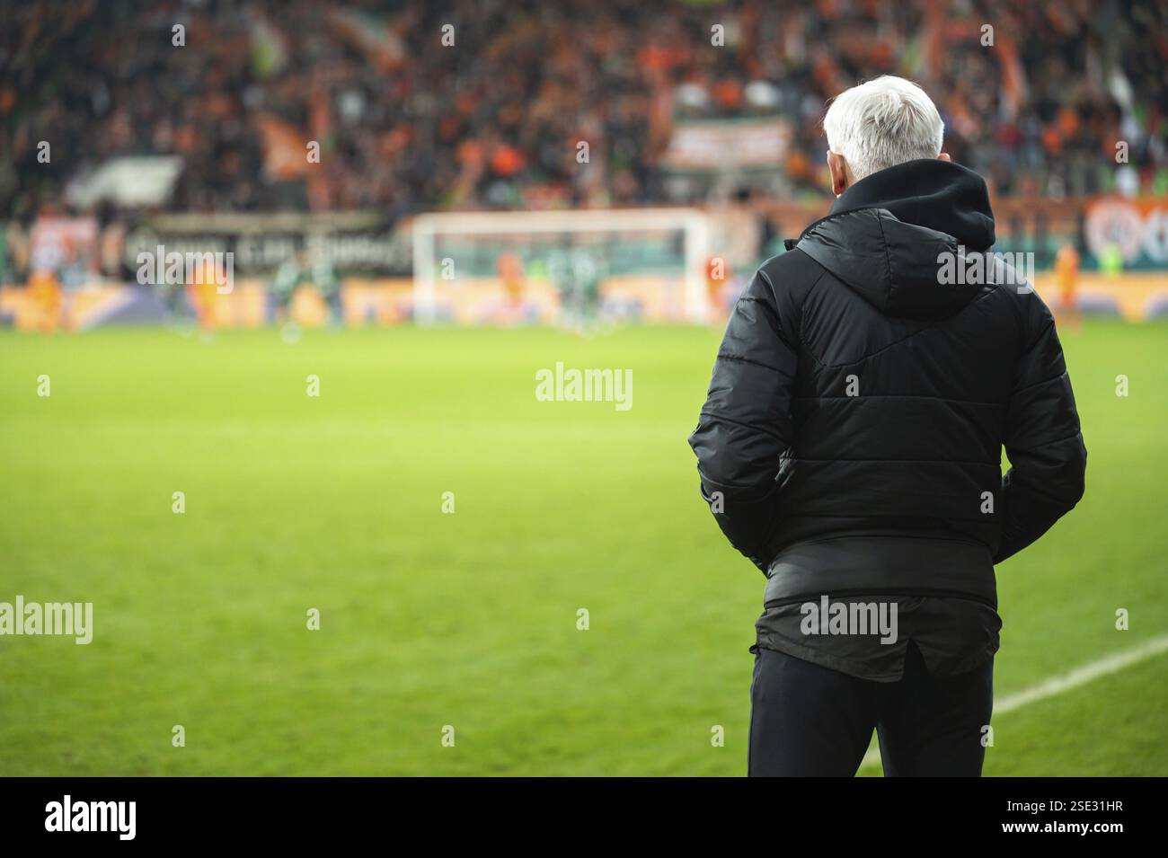Der Rücken des Cheftrainers und das Fußballspiel im Stadion im Hintergrund Stockfoto