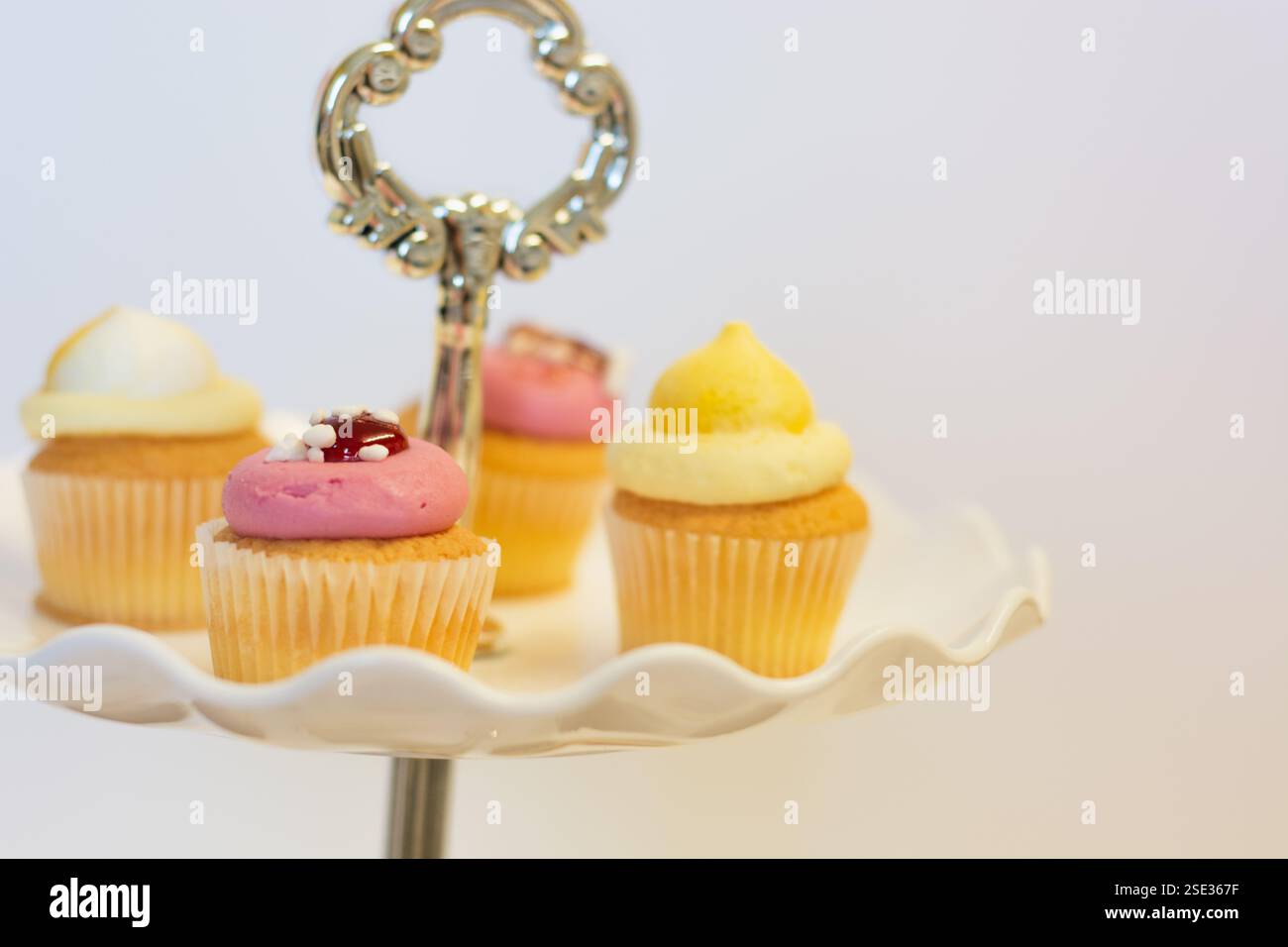 Erdbeeren- und Zitronencupcakes auf einem traditionellen Kuchenständer für Oster- und Nachmittagstee; Konzept für Teatime, Geburtstage und Muttertag. Stockfoto