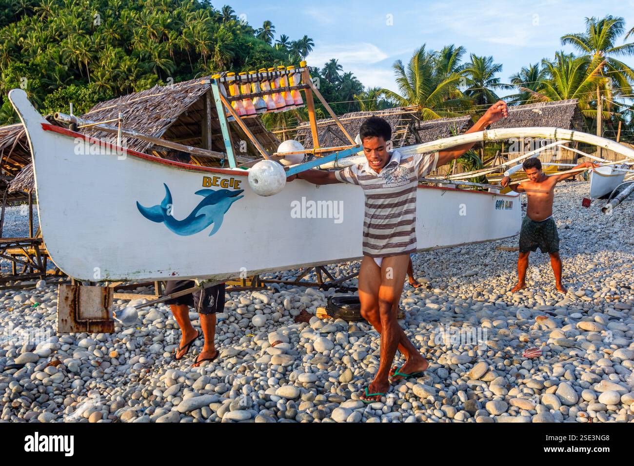 Eine Gruppe philippinischer Fischer praktiziert Bayanihan und trägt eine banca von der Küste zum Meer in Surigao Philippinen Stockfoto Eine Gruppe philippinischer Fischer praktiziert Bayanihan und trägt eine banca von der Küste zum Meer in Surigao Philippinen Stockfoto