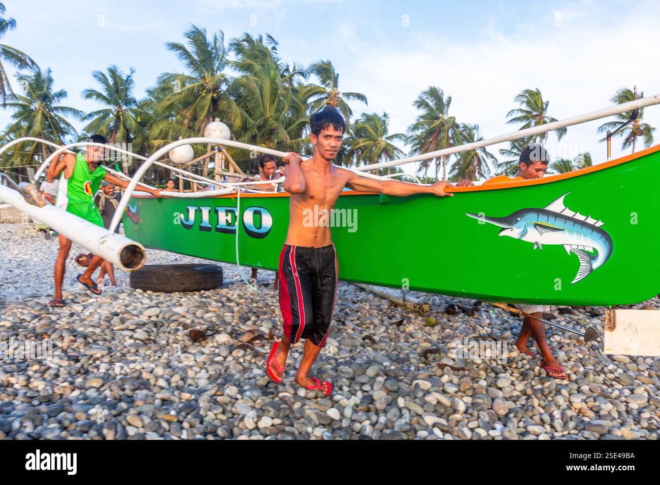 Eine Gruppe philippinischer Fischer praktiziert Bayanihan und trägt eine banca von der Küste zum Meer in Surigao Philippinen Stockfoto Eine Gruppe philippinischer Fischer praktiziert Bayanihan und trägt eine banca von der Küste zum Meer in Surigao Philippinen Stockfoto