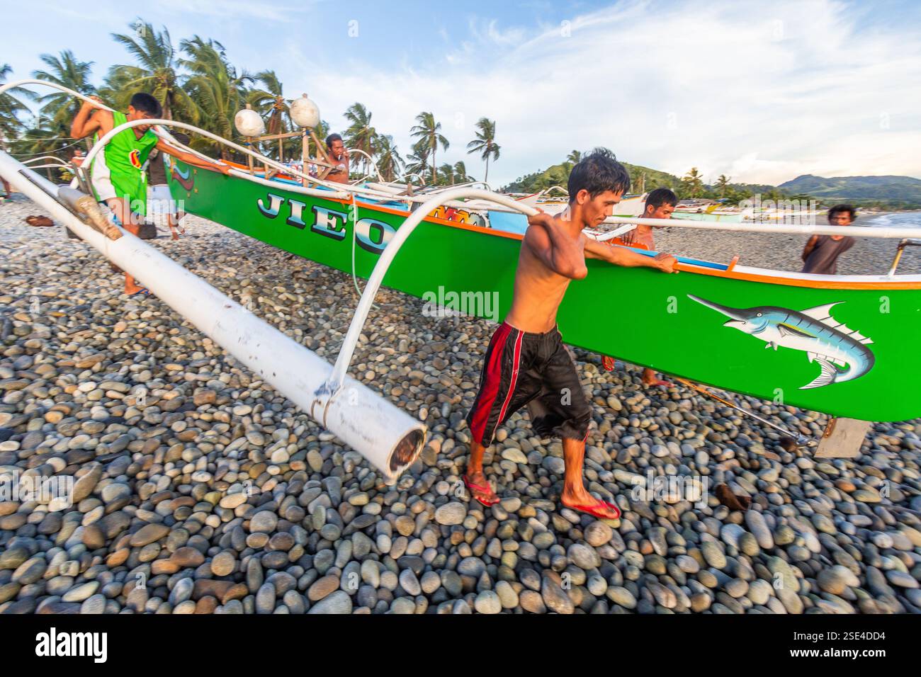 Eine Gruppe philippinischer Fischer praktiziert Bayanihan und trägt eine banca von der Küste zum Meer in Surigao Philippinen Stockfoto Eine Gruppe philippinischer Fischer praktiziert Bayanihan und trägt eine banca von der Küste zum Meer in Surigao Philippinen Stockfoto