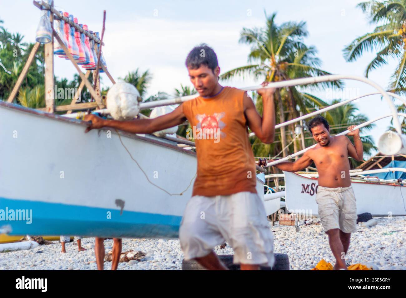 Eine Gruppe philippinischer Fischer praktiziert Bayanihan und trägt eine banca von der Küste zum Meer in Surigao Philippinen Stockfoto Eine Gruppe philippinischer Fischer praktiziert Bayanihan und trägt eine banca von der Küste zum Meer in Surigao Philippinen Stockfoto