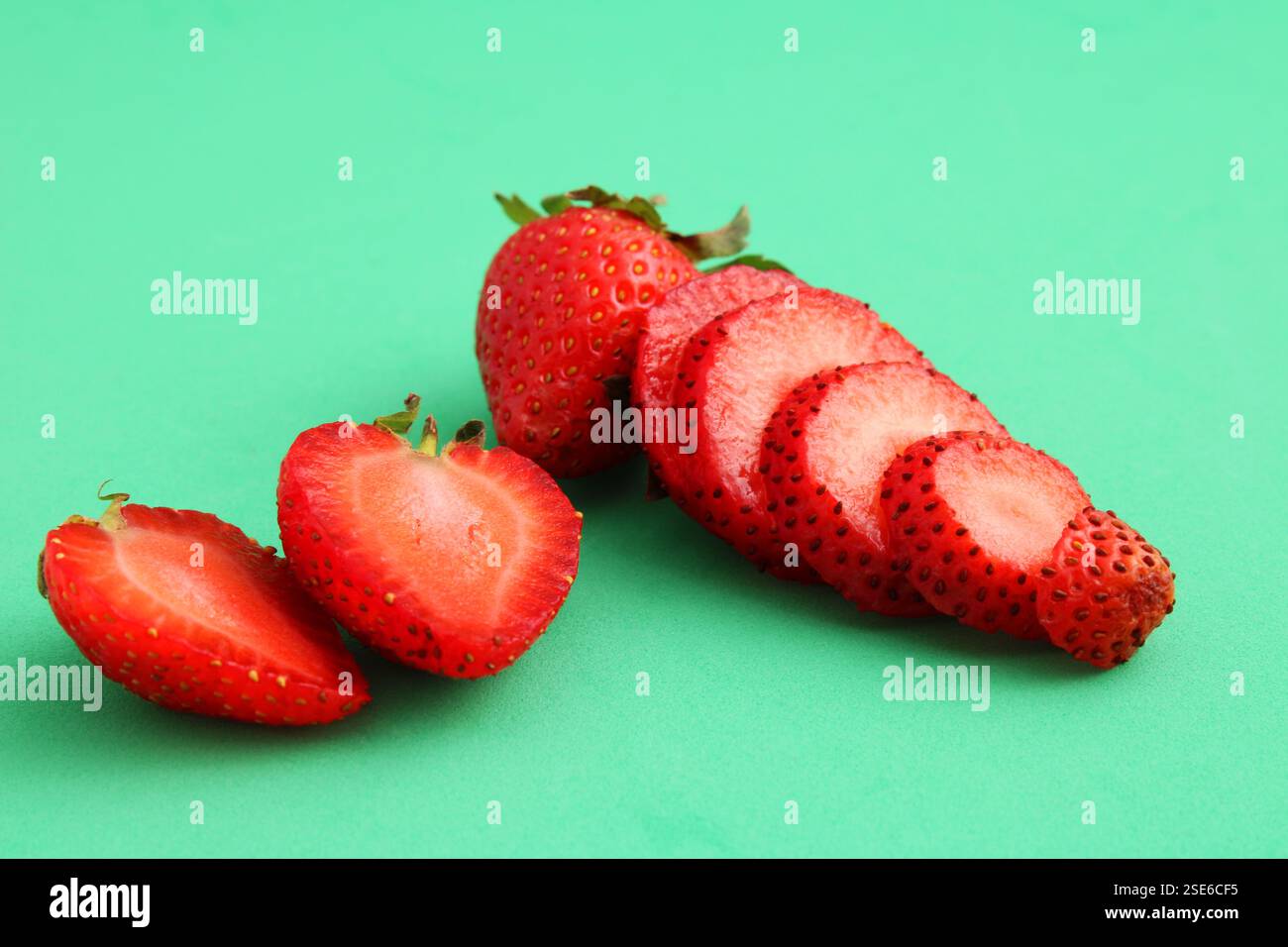Drei reife Erdbeeren, eine in Scheiben geschnittene ​​and, eine in zwei Hälften geschnitten Stockfoto