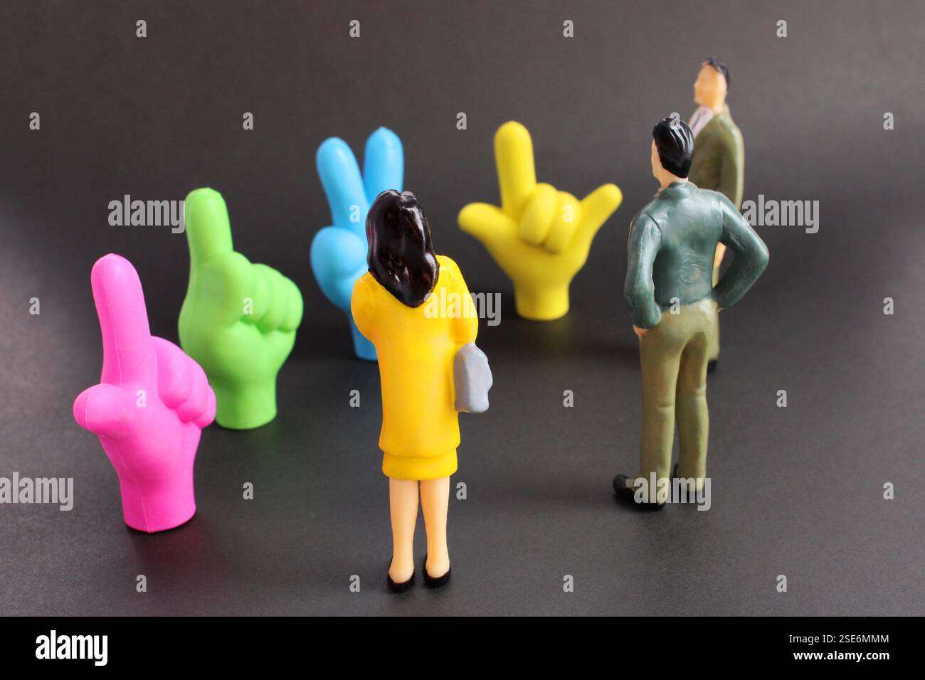 Führungskräfte beobachten vier bunte Hände, die unterschiedliche Zeichen machen Stockfoto