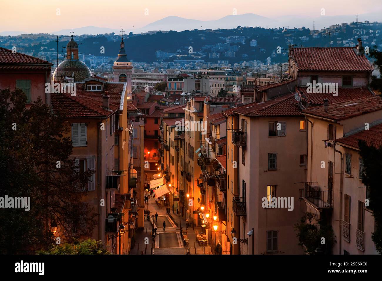 Ein bezaubernder abendlicher Blick auf die Altstadt von Nizza mit warmen Lichtern, die enge Gassen, historische Dächer und ferne Hügel unter dem sanften Glanz von t erhellen Stockfoto