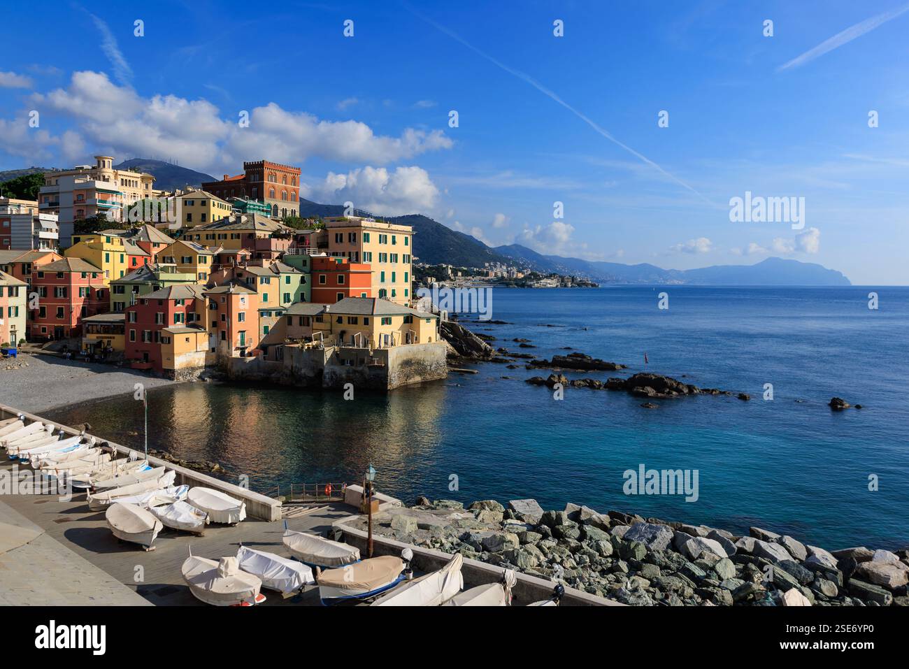 Boccadasse, ein charmantes Küstenviertel in Genua, Italien. Farbenfrohe Häuser säumen die felsige Küste, mit Booten, die am Ufer ruhen. Die blaue Meeresstraße Stockfoto