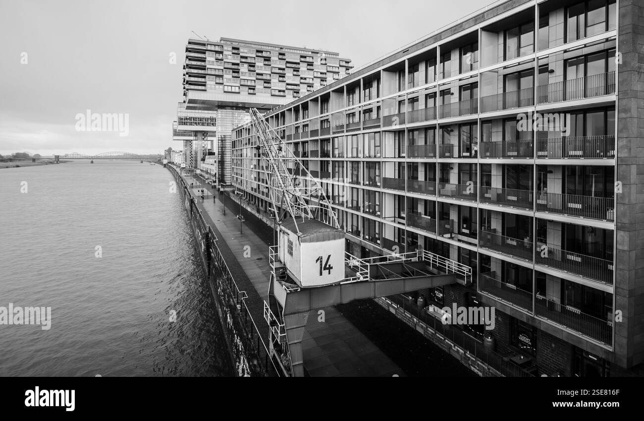 Blick auf den Fluss mit eleganten, modernen Gebäuden mit einzigartigem architektonischem Design und Blick auf das Wasser. Der graue Himmel trägt zum urbanen Ambiente bei. Stockfoto