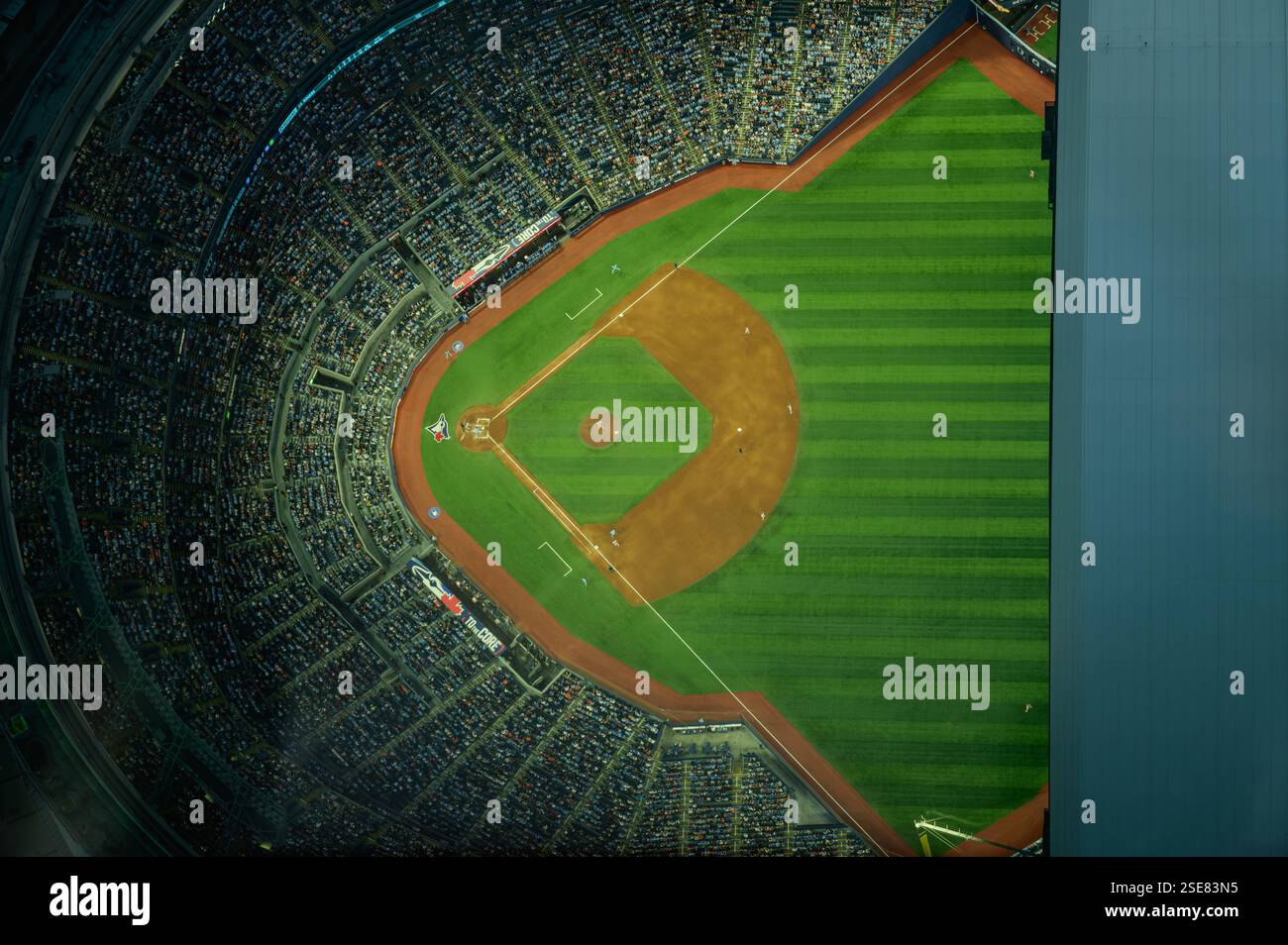 Ein lebhaftes Baseballstadion erfüllt mit begeisterten Fans unter dem warmen Licht der Abendlichter. Die Spieler spielen in einem intensiven Spiel, in dem sie Athleten zeigen Stockfoto