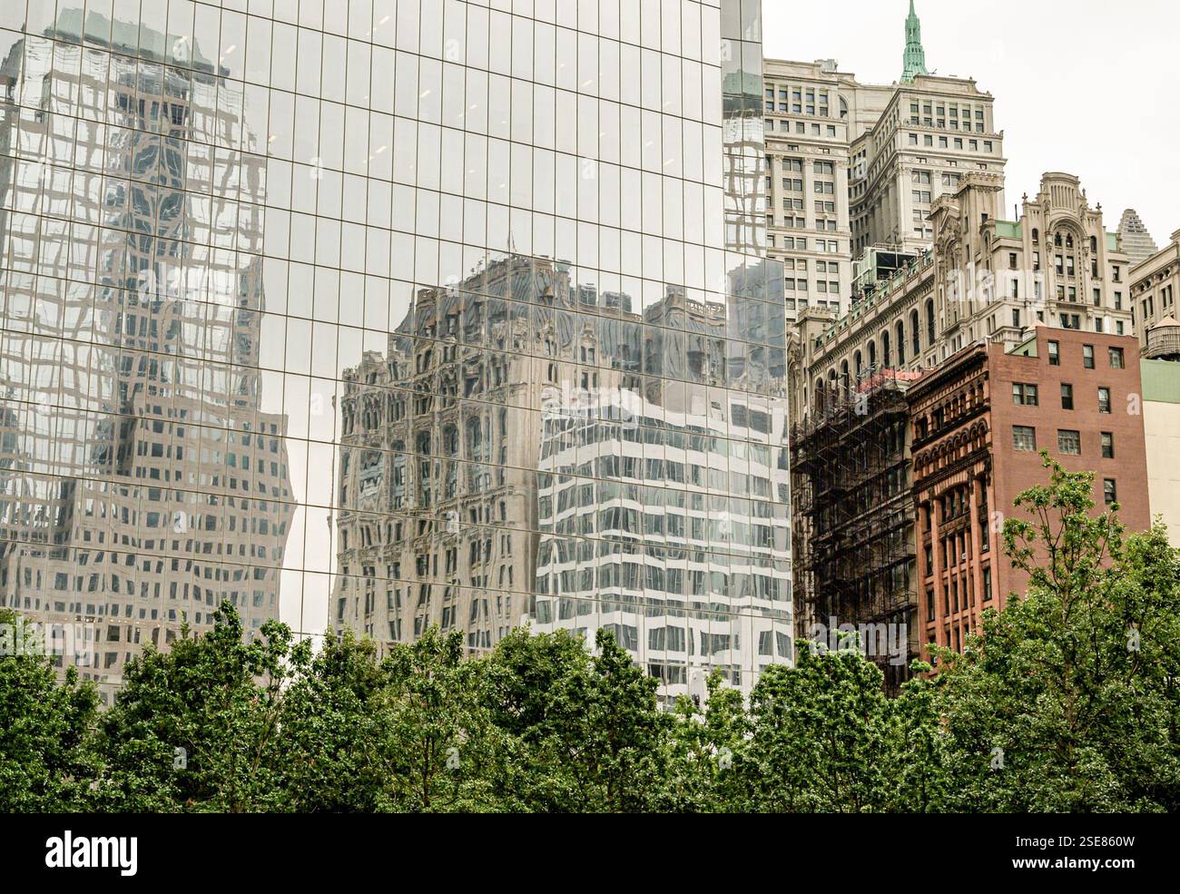 In einer urbanen Landschaft spiegeln sich hohe Gebäude auf einer schlanken Glasfassade wider. Die Mischung aus alter und neuer Architektur zeigt die Stadtentwicklung im Vergleich zu einem Stockfoto