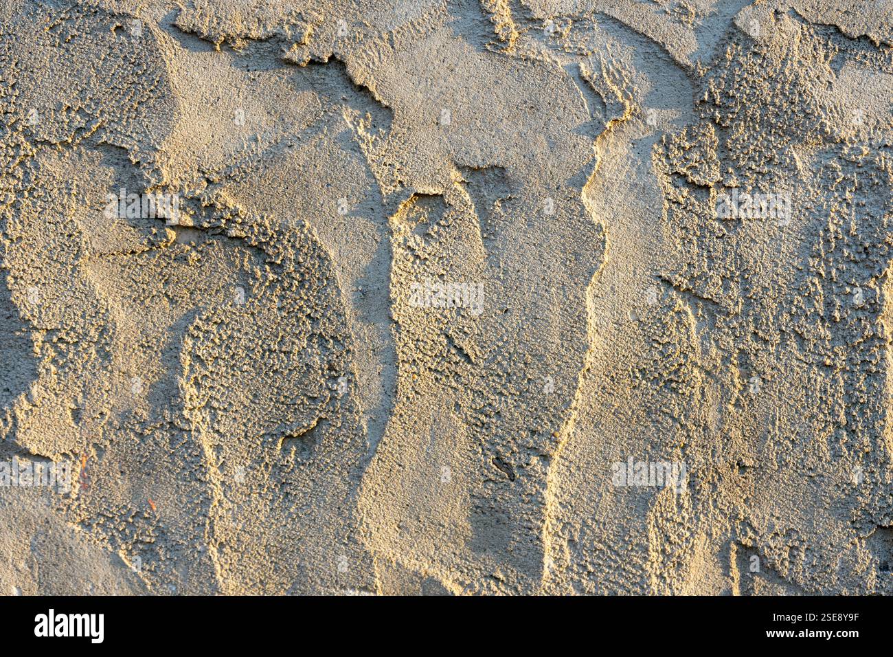 Die Oberfläche weist komplizierte Muster auf, die von trockenem Sand gebildet und von warmem Sonnenlicht beleuchtet werden. Die Texturen erzeugen einen optisch ansprechenden Effekt Stockfoto