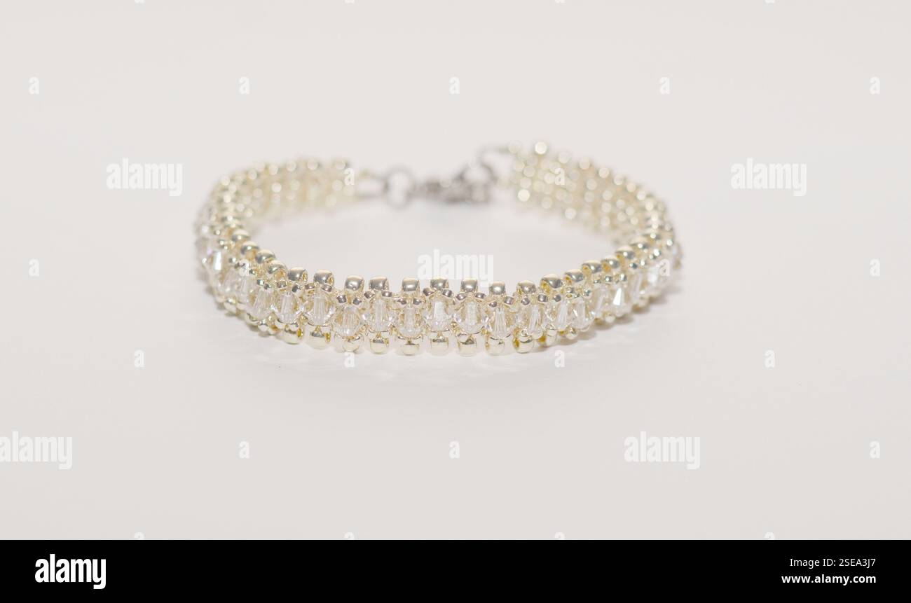 Elegantes, handgefertigtes Armband mit Perlen aus klarem Kristall und Silberperlen, das ein raffiniertes und zartes Design auf weißem Hintergrund schafft Stockfoto