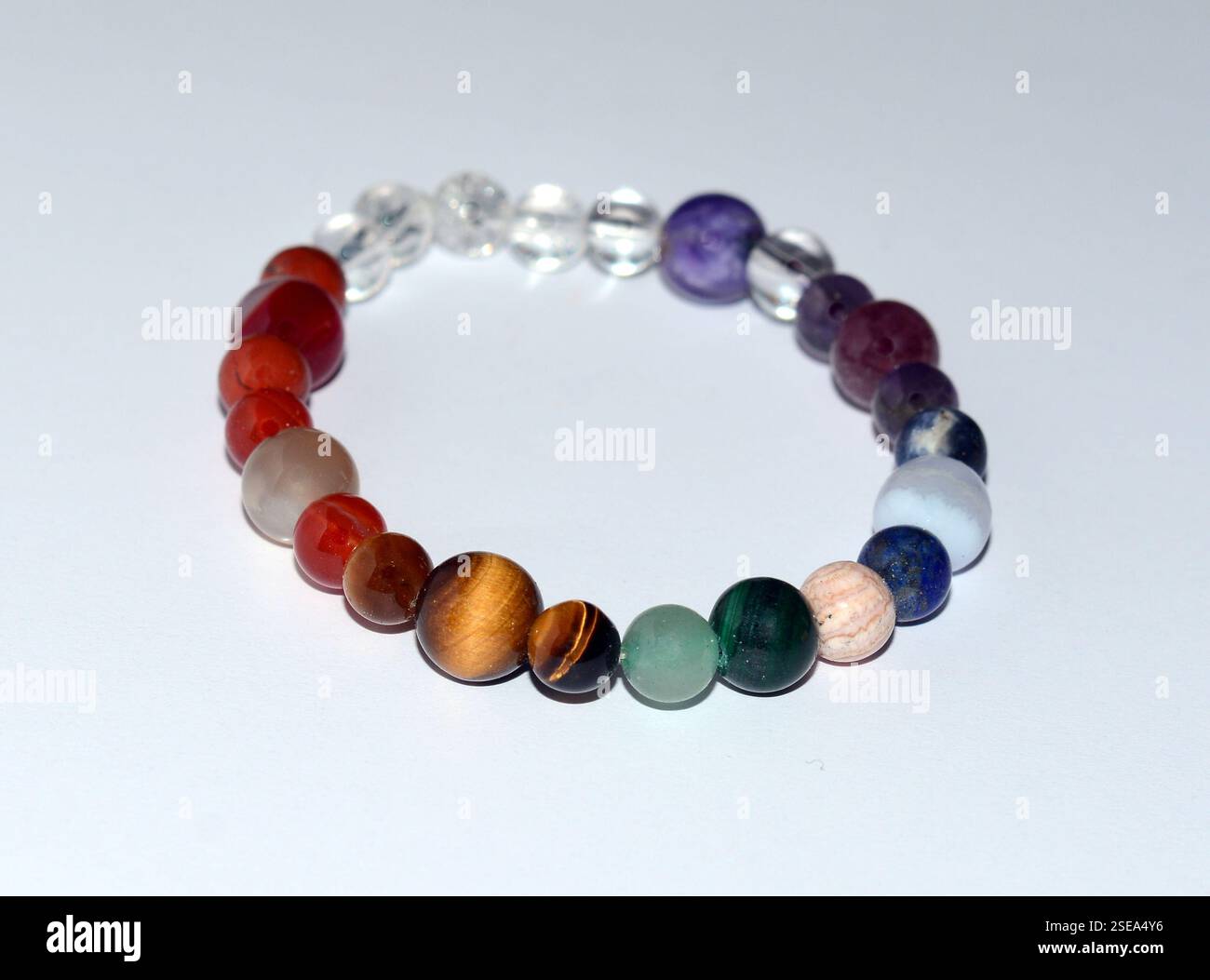 Elegantes und einzigartiges handgefertigtes Chakra-Armband mit Mineralperlen, das lebendige Farben und natürliche Schönheit vor einem sauberen weißen Hintergrund präsentiert Stockfoto