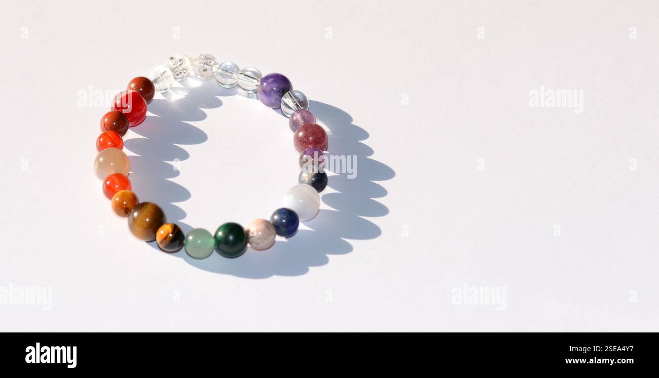 Elegantes und einzigartiges handgefertigtes Chakra-Armband mit Mineralperlen, das lebendige Farben und natürliche Schönheit vor einem sauberen weißen Hintergrund präsentiert Stockfoto