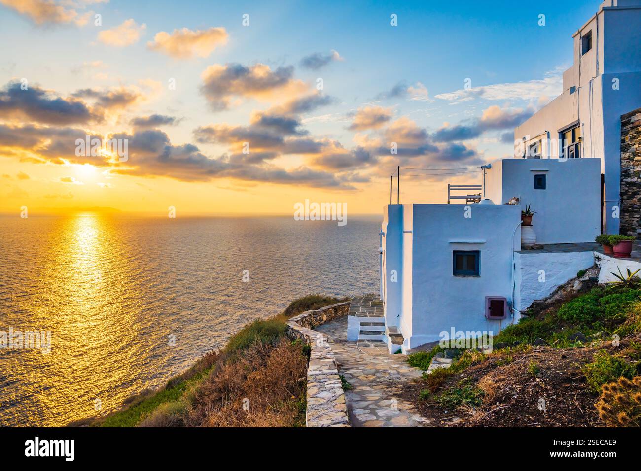 Sonnenaufgang über der felsigen Küste der Insel Sifnos mit typischen weißen Häusern im Vordergrund im Dorf Kastro, Kykladen, Griechenland Stockfoto