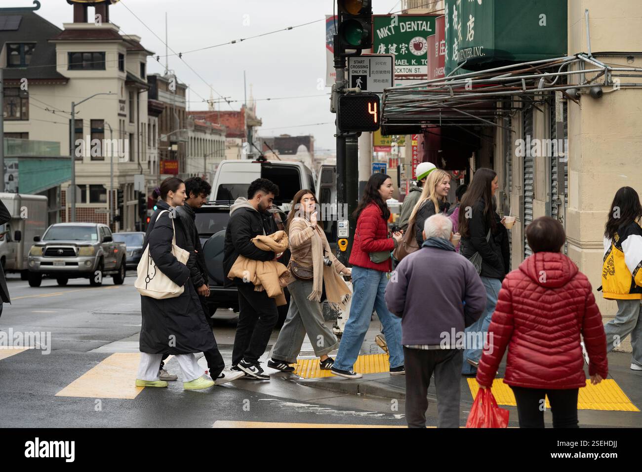 Fußgänger überqueren eine Straße an einer Kreuzung in San Franciscos Chinatown in der Nähe der Stockton Street. Das Signal zeigt 4 Sekunden bis zum Überqueren an. Stockfoto