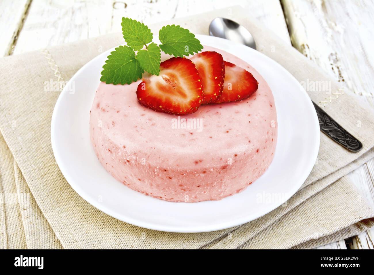 Dessert Panna Cotta von Quark und Erdbeere, Minze und Beeren in eine Platte auf eine Serviette auf dem Hintergrund Licht Holzbretter Stockfoto