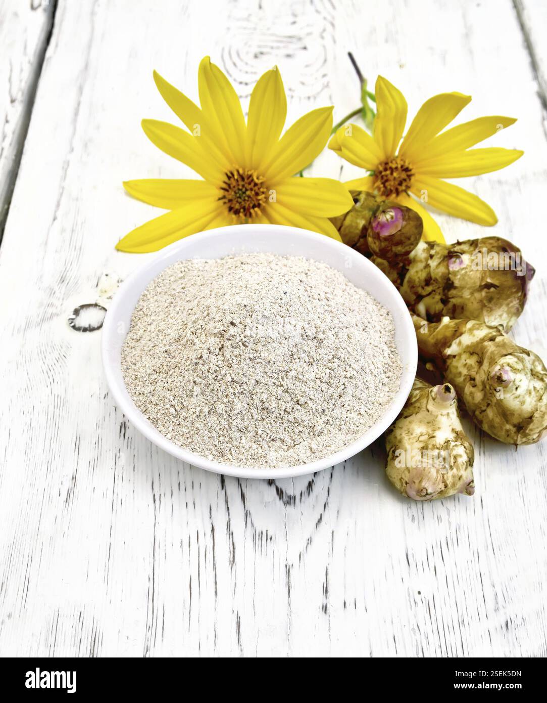 Mehl von Jerusalem Artischocke in eine Schüssel mit Gemüse und Blumen auf dem Hintergrund Licht Holzbretter Stockfoto