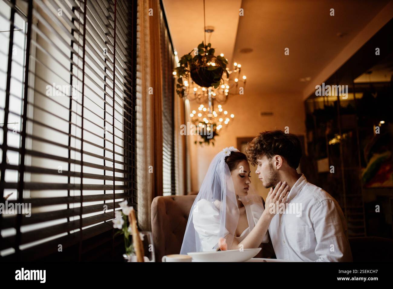 Braut und Bräutigam teilen sich eine intime Umarmung in einem sanften, eleganten Ambiente Stockfoto