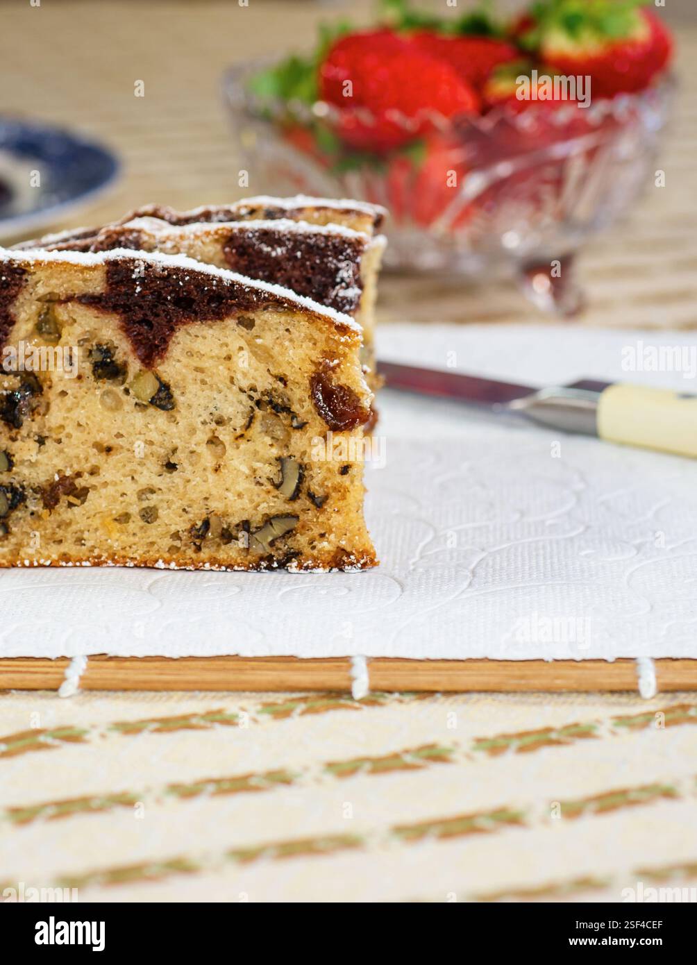 Marmorkuchen mit Rosinen und Walnüssen. Ein Stück Kuchen auf einem Teller mit einer Erdbeere. Stockfoto