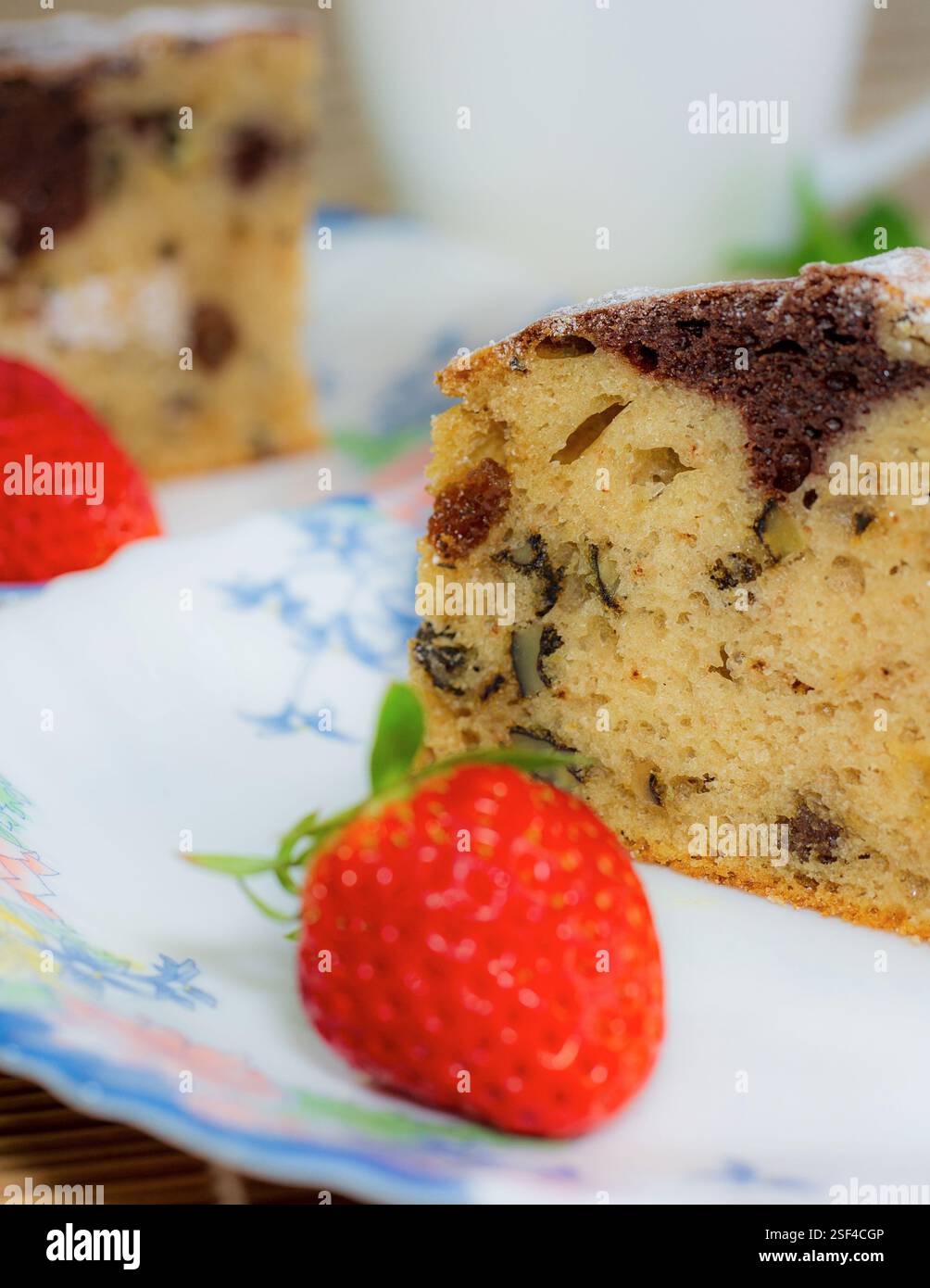 Marmorkuchen mit Rosinen und Walnüssen. Ein Stück Kuchen auf einem Teller mit einer Erdbeere. Stockfoto