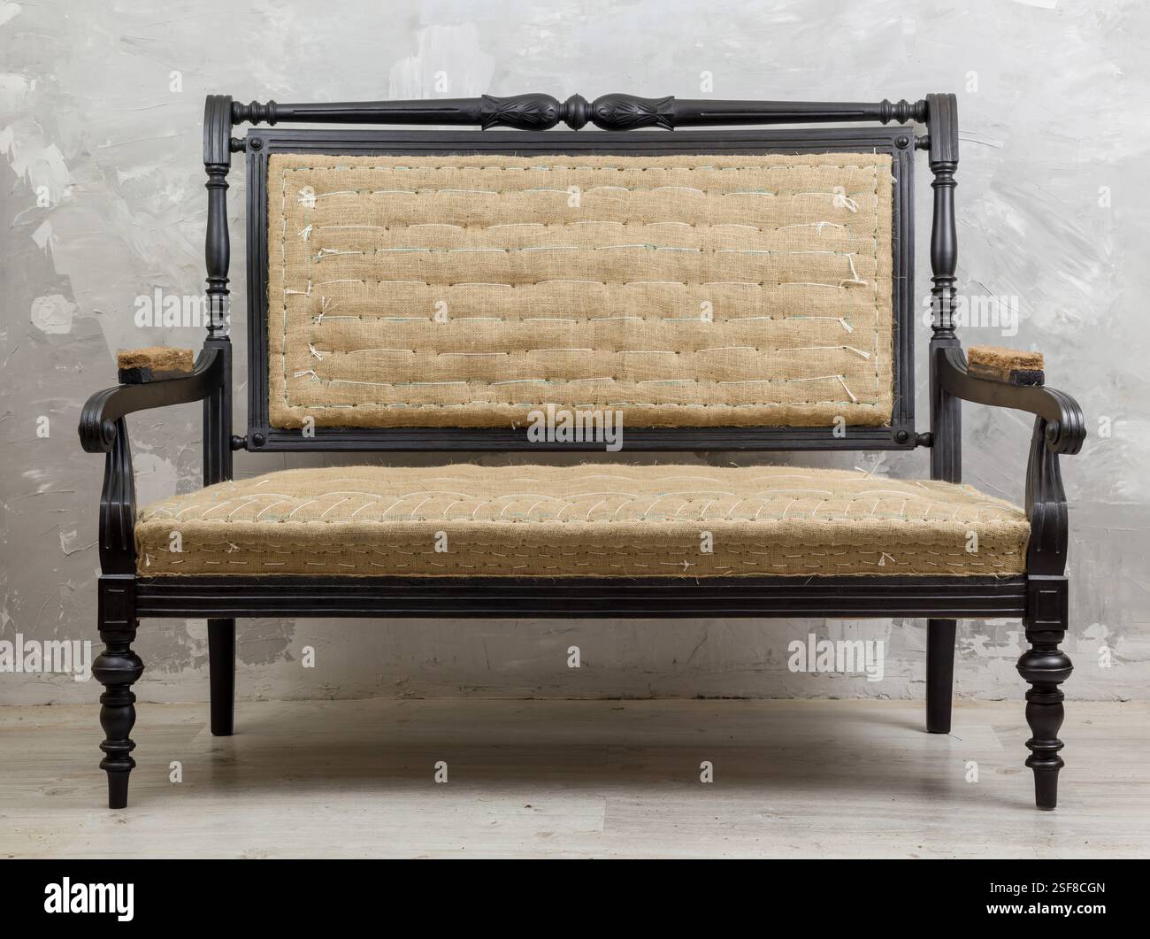 Antikes oder Vintage-Sofa mit dunklem Holzrahmen und hellen gewebten Polstern. Elegantes und klassisches Design vor strukturiertem Hintergrund. Perfekt für Pelze Stockfoto