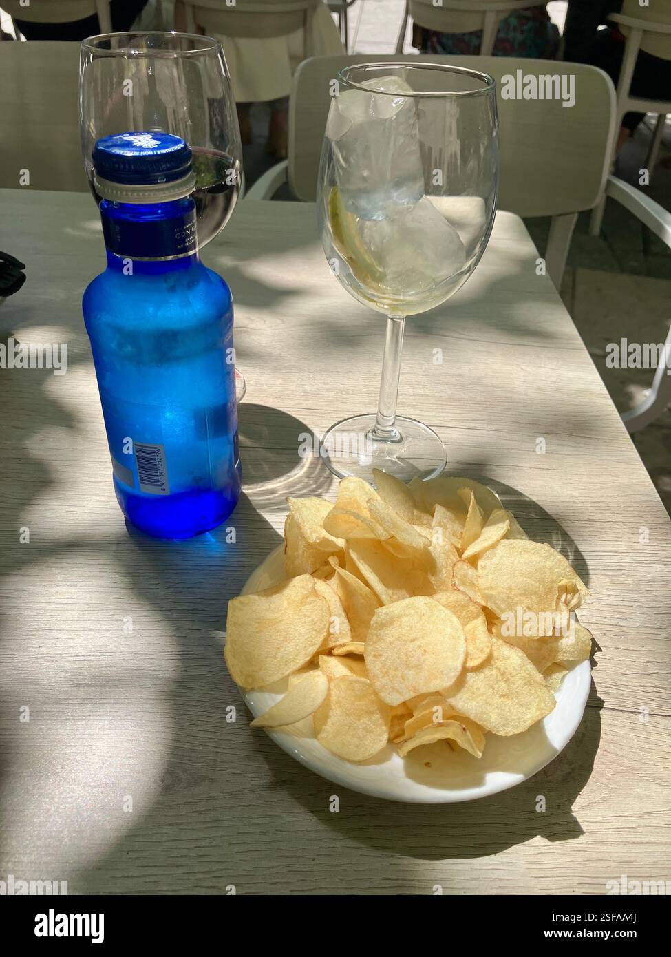 Wasser, Rotwein und Kartoffelchips. Ein Snack in Spanien. - Smartphone-aufgenommenes Stockfoto