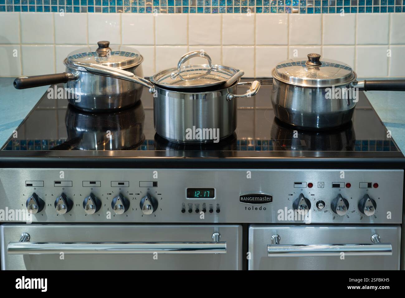 A Rangemaster Toldeo - ein traditioneller Ofen in einer typisch englischen Küche mit Edelstahlkasserollen auf dem Kochfeld. Konzept: Hausmannskost. UK Stockfoto