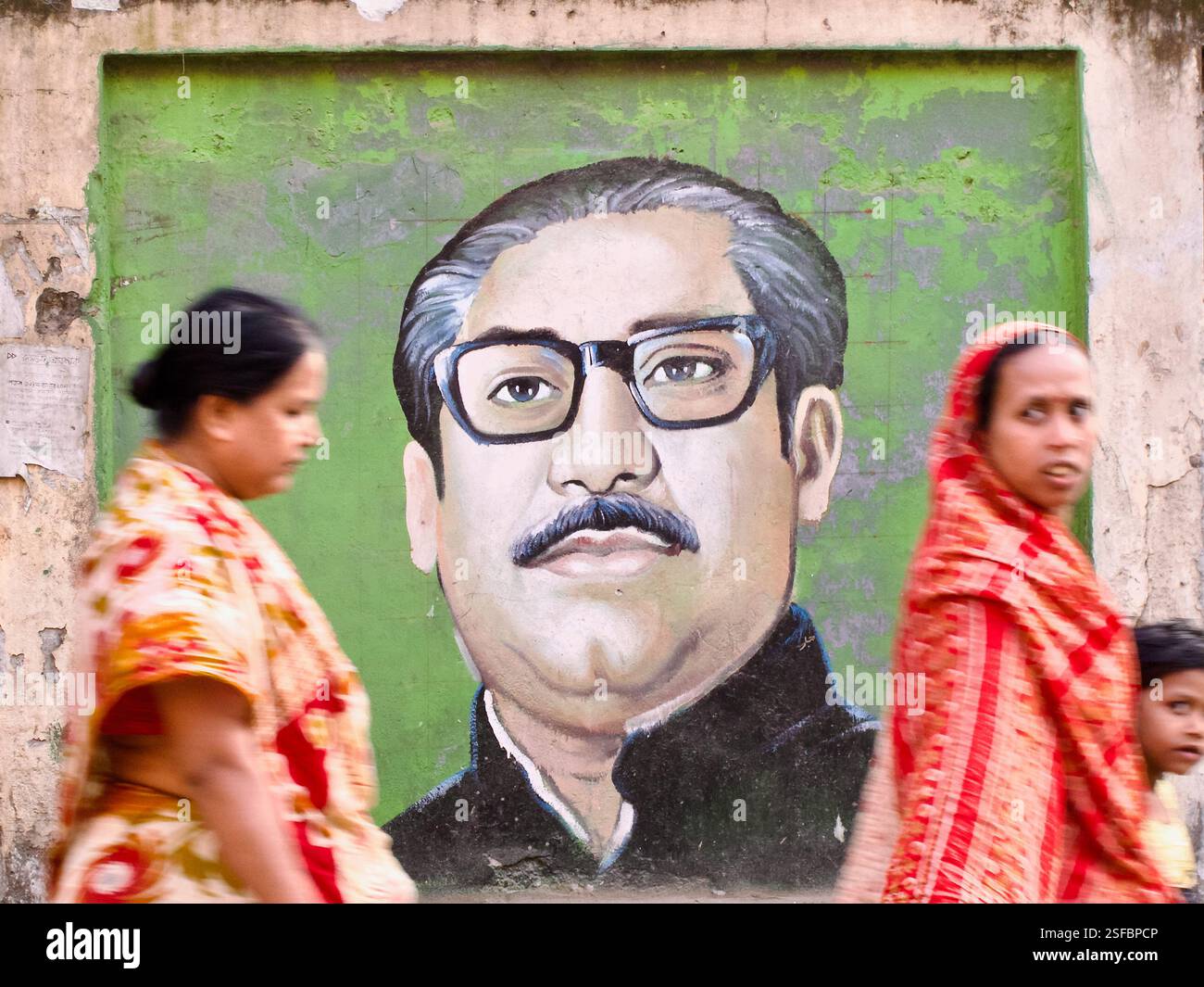 Ein Wandgemälde von Scheich Mujibur Rahman in Dhaka, Bangladesch, mit verschwommenen Fußgängern, die vorbeiziehen, ein Ausdruck seines dauerhaften Einflusses im täglichen Leben. Stockfoto