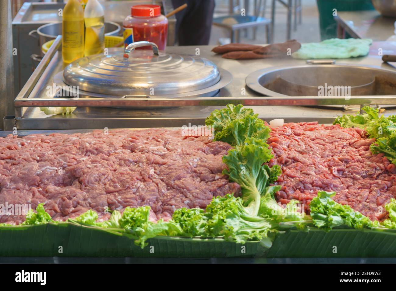 Aus nächster Nähe sehen Sie rohes, gehacktes Schweinefleisch auf Bananenblättern, garniert mit frischem Salat an einem belebten Street Food Stand. In der Einrichtung wird der hervorgehoben Stockfoto
