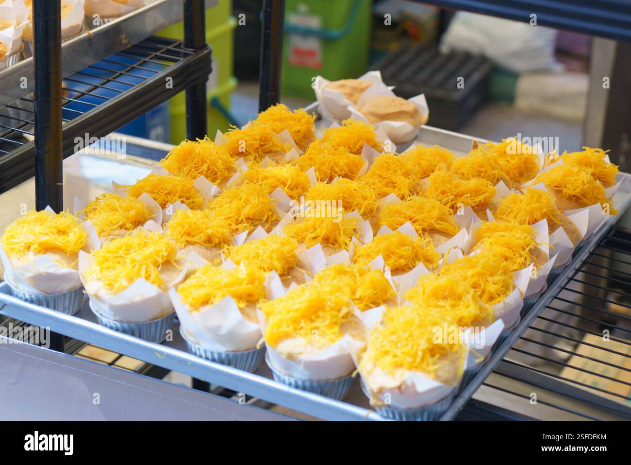 Nahaufnahme von weichen, flauschigen Cupcakes, gekrönt mit feinen Fäden aus goldenen Eiern (Foi Thong), ausgestellt an einem Street Food Stand. Dieses beliebte Thai Stockfoto
