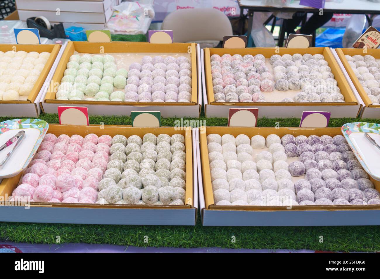 Nahaufnahme verschiedener japanischer Mochi in Pastelltönen (weiß, Grün, Rosa und Lila), die ordentlich in Tabletts angeordnet sind. Die weiche und zähe Textur, leicht Stockfoto