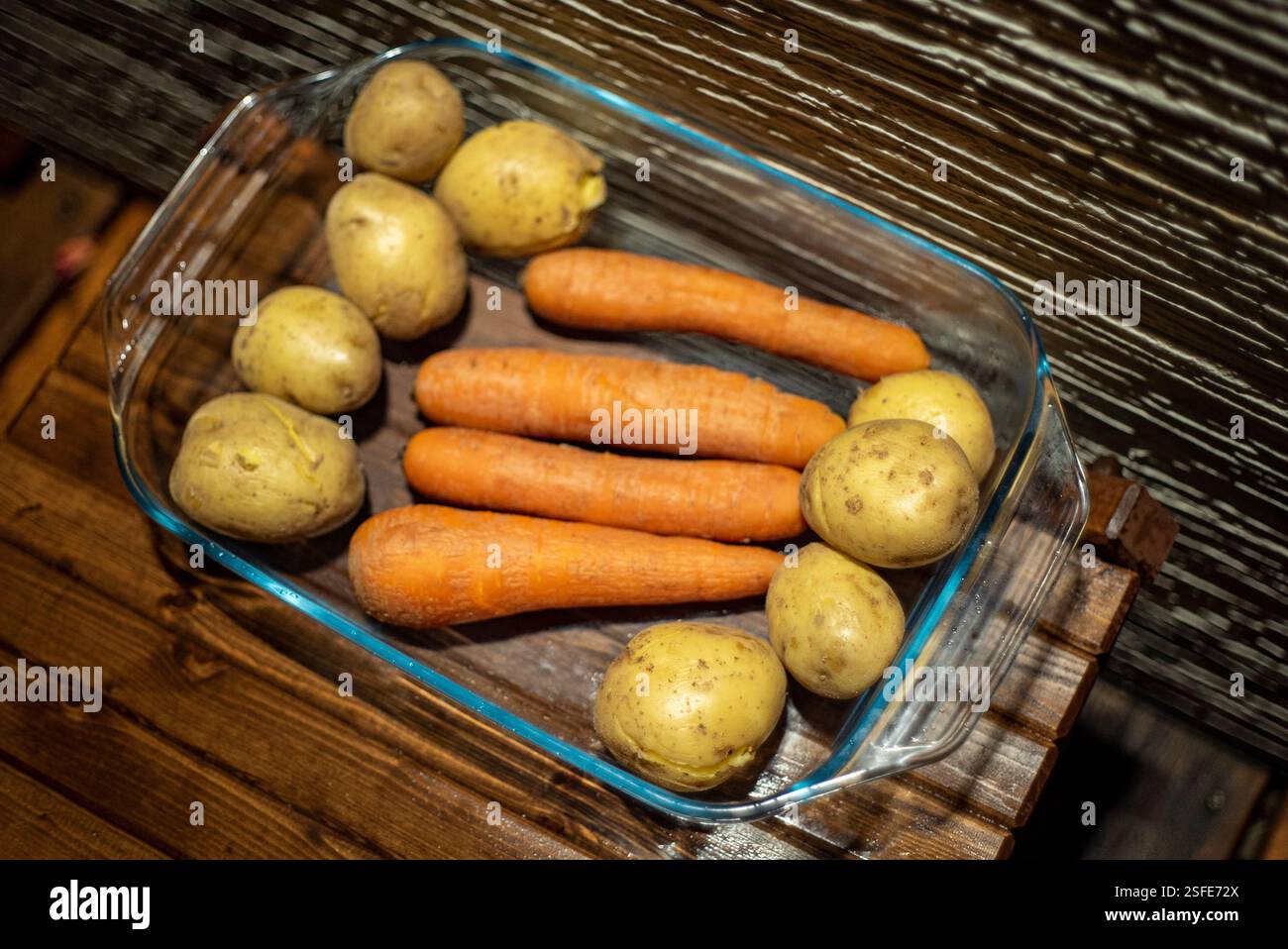 Ganze Karotten und Kartoffeln auf einem Glastablett, Nachtszene Stockfoto