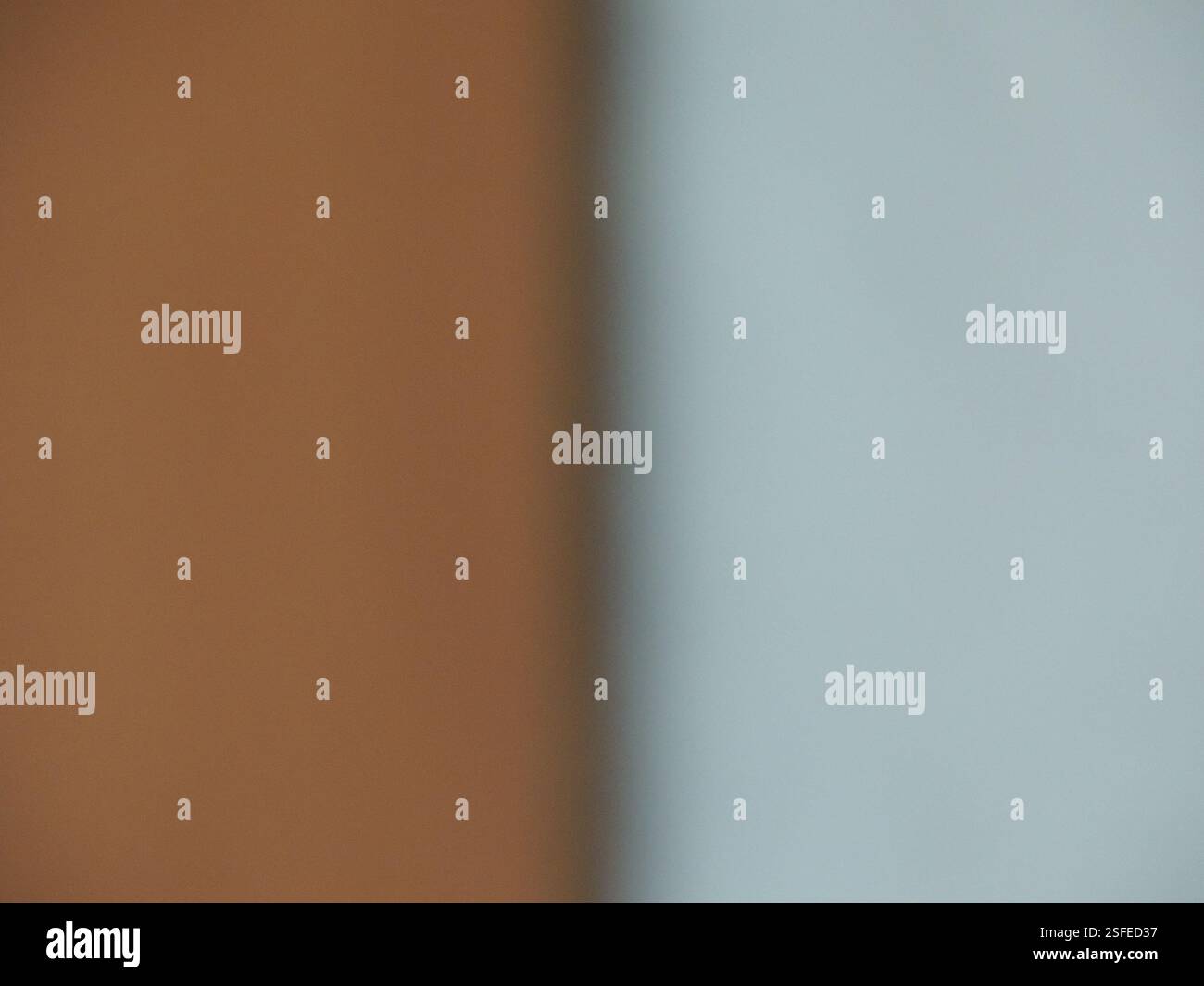 Grau-brauner, verschwommener Hintergrund, geteilt durch einen Schattenstreifen in zwei gleiche Teile, abstraktes einfaches zweifarbiges Bokeh mit verschwommener Textur und leerem Kopierraum Stockfoto