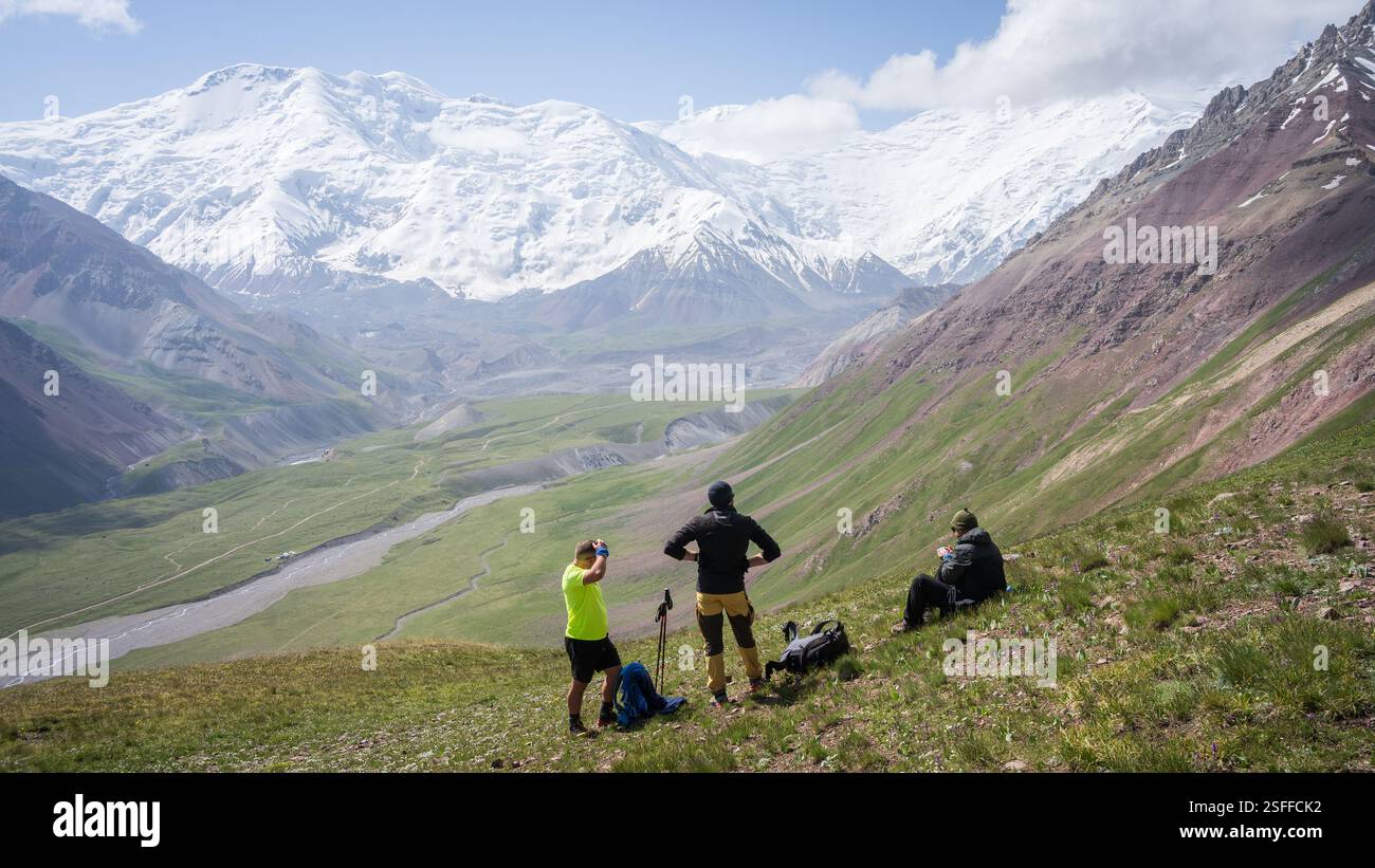 Wanderer genießen die Aussicht auf das grüne Alpental mit den massiven Gletschern des Pamir-Gebirges in Kirgisistan Stockfoto