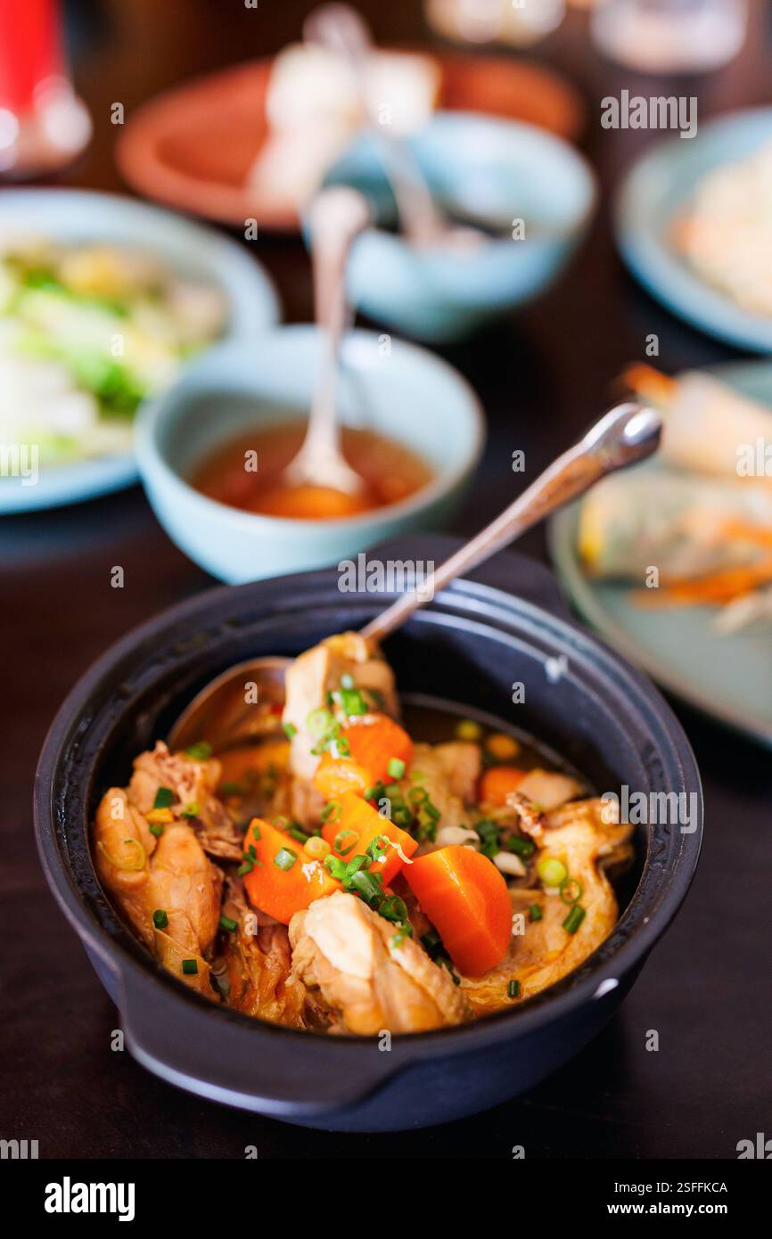 Ein herzhaftes Gericht mit Ragu GA (vietnamesischer Hühnereintopf), serviert in einem Tontopf. Der Eintopf besteht aus zarten Hähnchenstücken, Karotten, grünen Zwiebeln und Beilagen Stockfoto