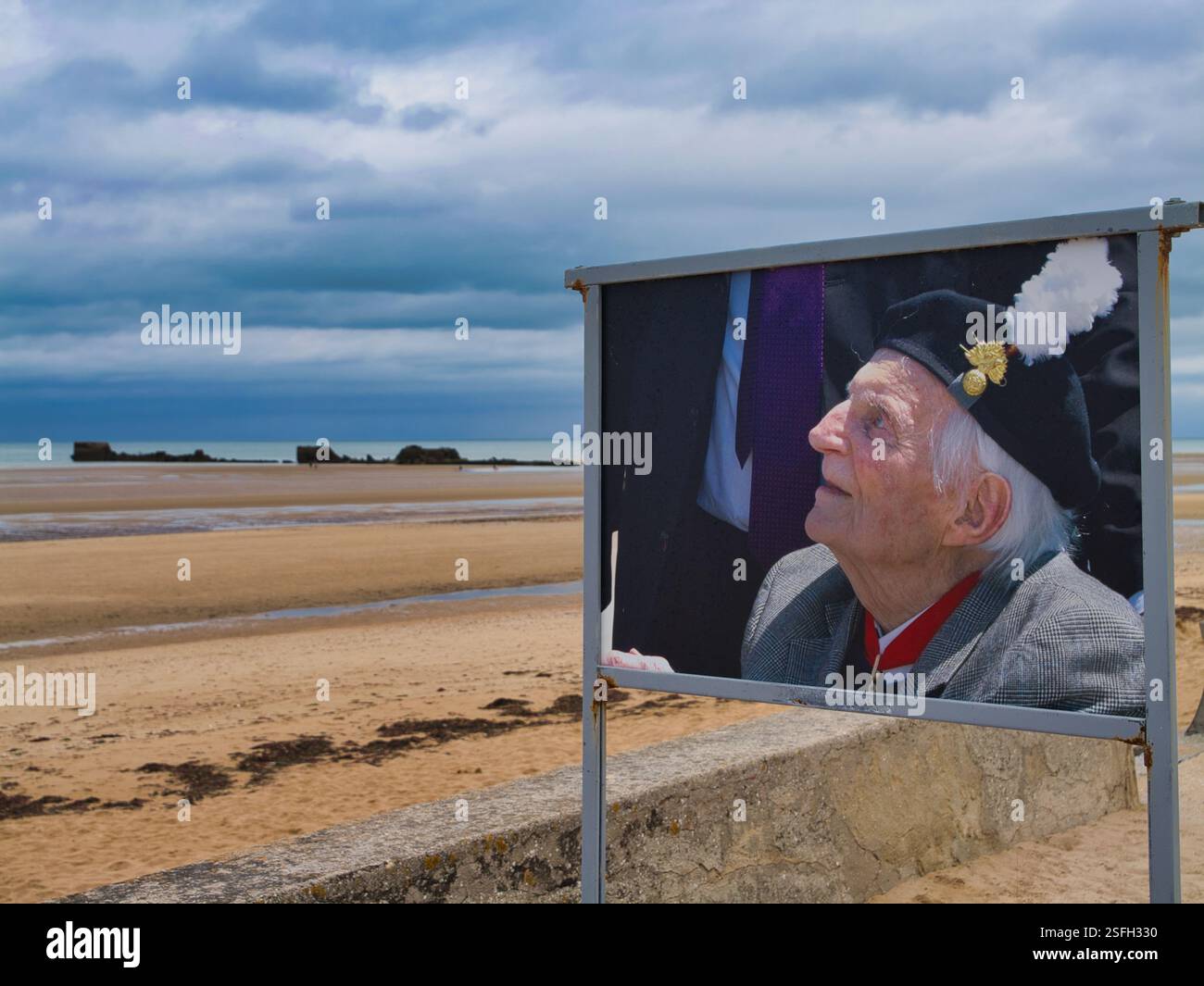 Asnelles, Frankreich - 2. September 24: In Asnelles, Normandie, Frankreich, ein Bild eines Veteranen Soldaten gegen die Überreste der Mulberry-Häfen in der Nähe von Gold Beac Stockfoto