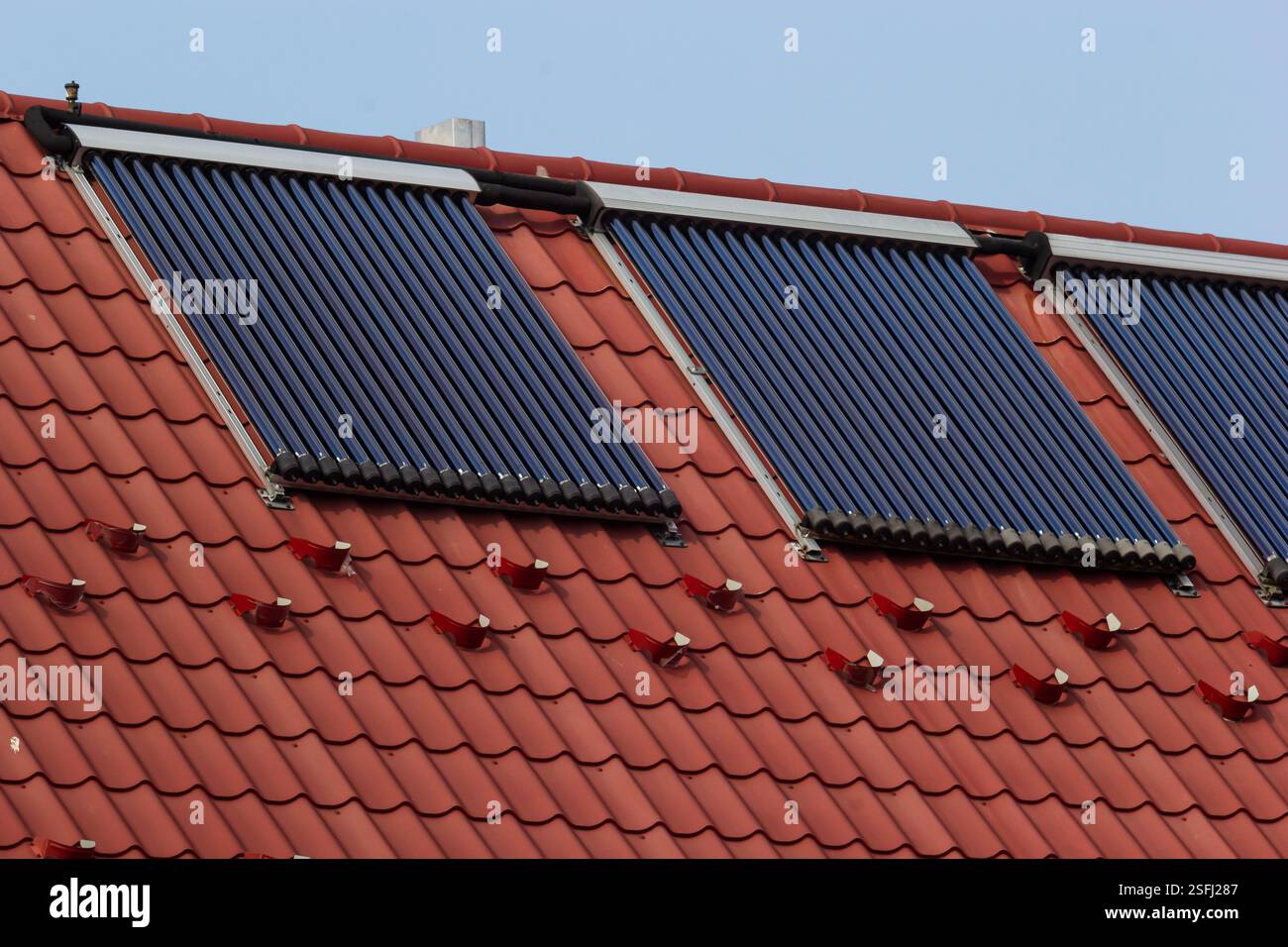 Solarpaneele, die auf einem geneigten roten Ziegeldach installiert sind, zeigen einen umweltfreundlichen Ansatz zur Energienutzung. Das Setup fördert die Nachhaltigkeit in Resi Stockfoto