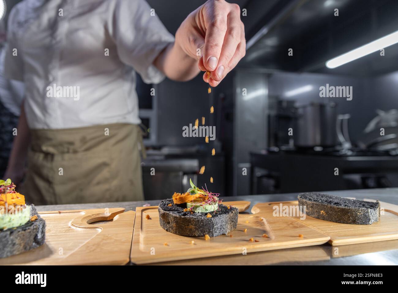 Der professionelle Koch verleiht einem Gourmet-Schwarzbrot in einer kommerziellen Küche einen letzten Schliff Stockfoto
