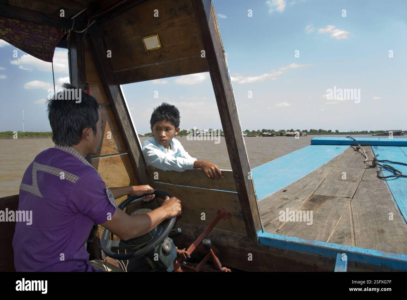 Der Junge spricht mit dem Steuermann auf einem Boot, das zum Tonle SAP Lake fährt. Stockfoto