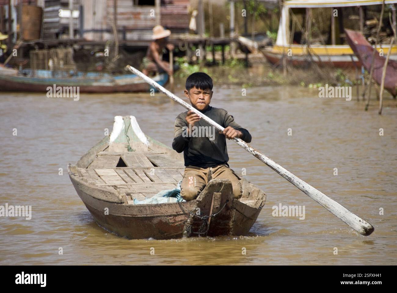 Junge paddelt mit einem Boot auf dem Fluss in der Nähe des Tonle SAP Lake. Stockfoto