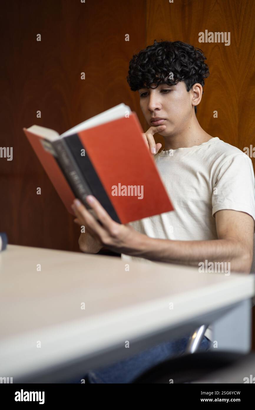 Ein engagierter Schüler, der unermüdlich für eine bevorstehende Prüfung studiert. Perfekt für Themen wie Prüfungsvorbereitung, Konzentration, Bildung und akademische Entschlossenheit. Stockfoto