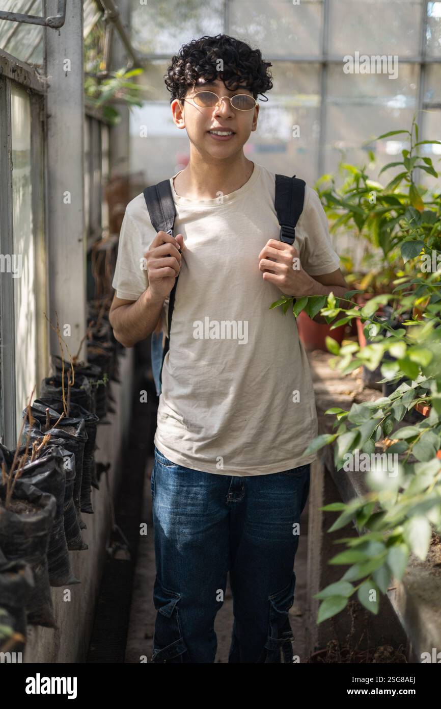 Ein junger Mensch, entspannt und mit einem Rucksack, genießt die friedliche Atmosphäre eines botanischen Gartens. Ideal für Themen wie Natur, Wellness und Jugend Stockfoto